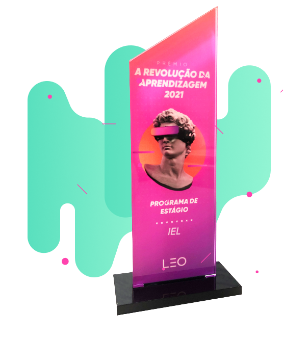 Um troféu moderno e estilizado em formato de prisma retangular, com uma base preta brilhante e um corpo transparente com gradiente de cores rosa e laranja. O troféu apresenta texto branco verticalizado que diz "PRÊMIO A REVOLUÇÃO DA APRENDIZAGEM 2021" na parte superior, seguido por uma imagem estilizada e moderna de uma escultura clássica com uma faixa rosa neon cobrindo os olhos. Abaixo da imagem da escultura, em letras menores, lê-se "PROGRAMA DE ESTÁGIO IEL" e, na base do corpo do troféu, o logotipo "LEO" em letras grandes e brancas.